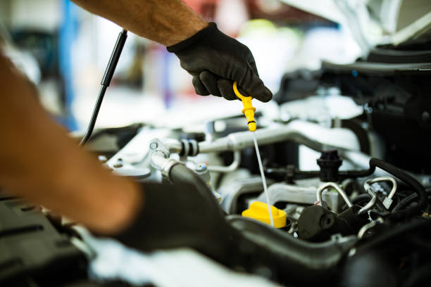 Close up of unrecognizable mechanic examining car oil in a repair shop.