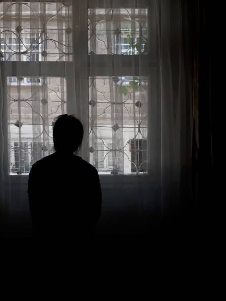 istock Female silhouette in dark room and window 1162112759