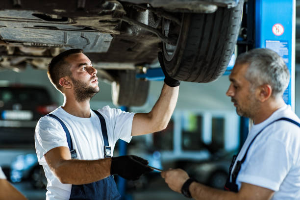 istock Car repairmen cooperating while working on a tire in a workshop. 1162112922