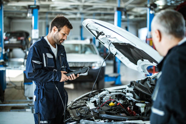 Auto mechanic working with car diagnostic tool in a repair shop.