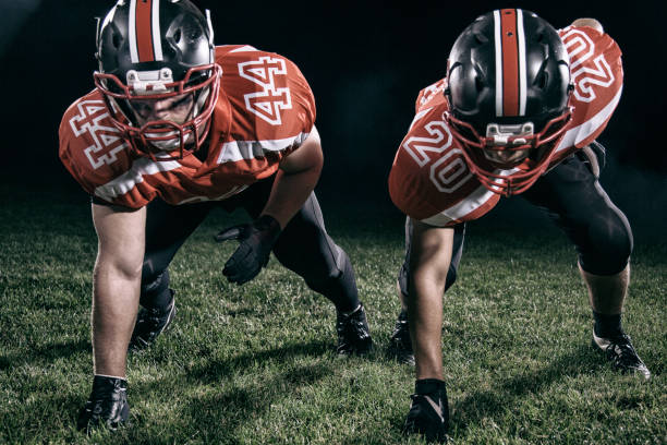 Start of a drive position of a two american football players in red dresses.