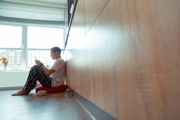 istock Freelancer sitting on floor near window and reading e-mail 1162121841