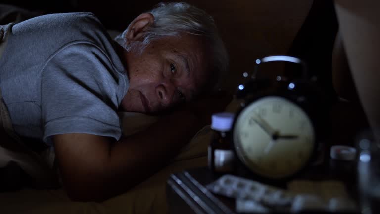 A depressed senior man lying in bed cannot sleep from insomnia