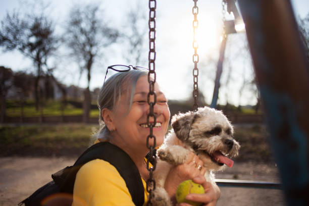 istock Senior woman sitting on swing with dog 1162122733