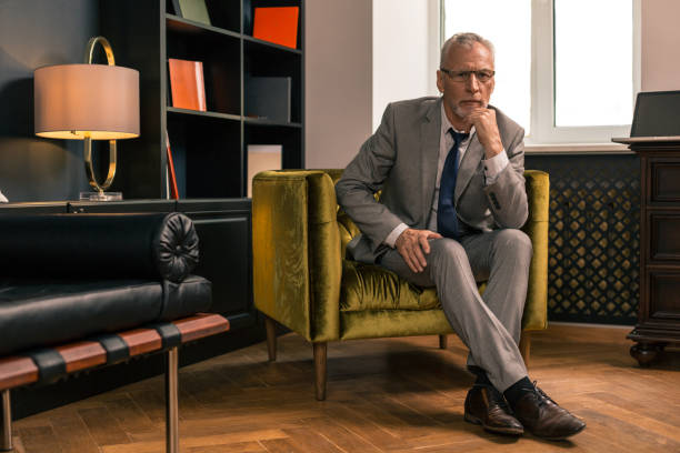 istock Elegant serious senior man sitting in his office 1162122864