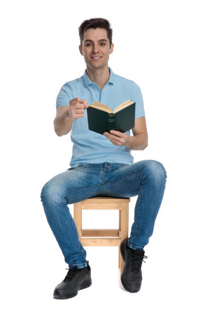 istock Handsome casual man pointing and holding a book 1162128022