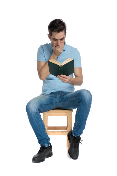 istock Shocked casual guy reading a book and covering his mouth 1162128262