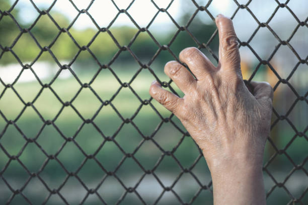 istock Aged hand on a chain fence 1162129469