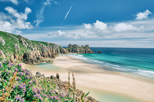 Scenic views across Pedn Vounder Beach towards Logan's Rock, Cornwall on a sunny June day.