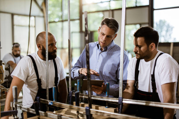 istock Young carpenters and their manager working on touchpad in a workshop. 1162130922