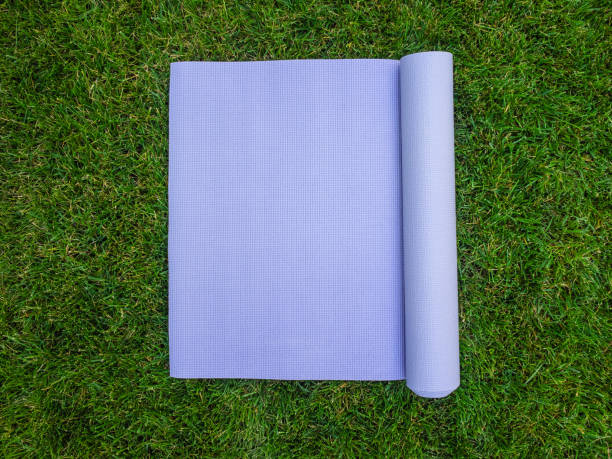 Purple yoga Mat on the grass. Mat for yoga, Pilates or fitness Purple yoga Mat on the grass. Mat for yoga, Pilates or fitness. Mat without people beach mat stock pictures, royalty-free photos & images