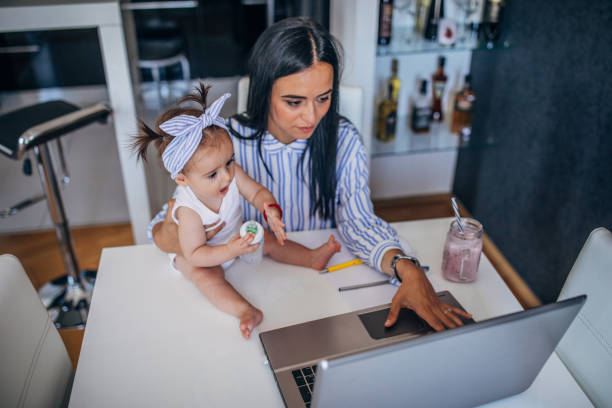 istock Modern mother holding a baby and using laptop 1162137117