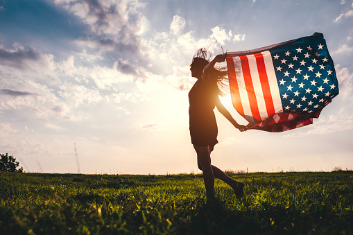 Gypsy young woman waving USA flag outdoor.