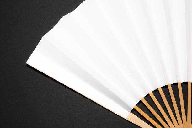 single whtie Japanese foldable fan on black background paper with copy spaceclose-up shot in studio