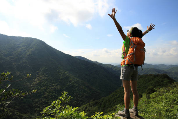 istock Cheering young woman backpacker enjoy the view at summer mountain peak 1162139310