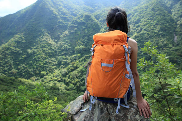istock Successful young woman backpacker enjoy the view on spring forest mountain cliff edge 1162140385
