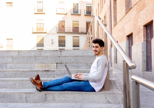 istock Young trendy man studying working on laptop computer blogging, chatting online and checking email in a european city outdoors. In student lifestyle, Technology, education and remote working concept. 1162141254