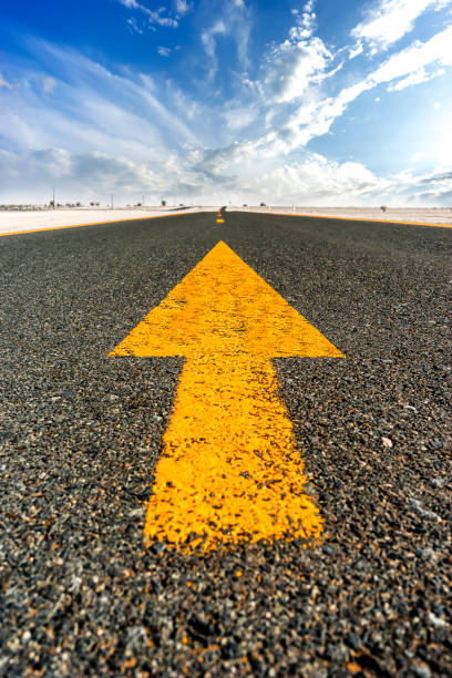 straight road with yellow road markings - arrow - asphalt highway desert valley imagens e fotografias de stock