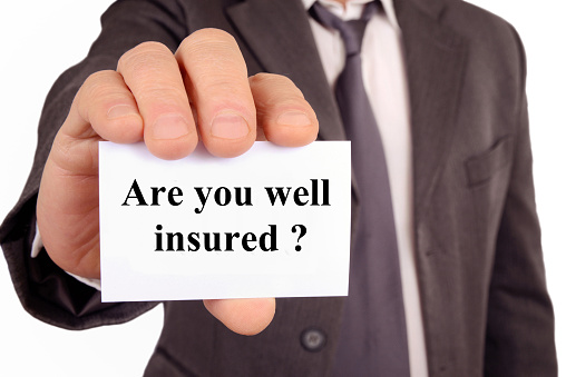 unrecognizable man holding a card on which is written are you well insured in English