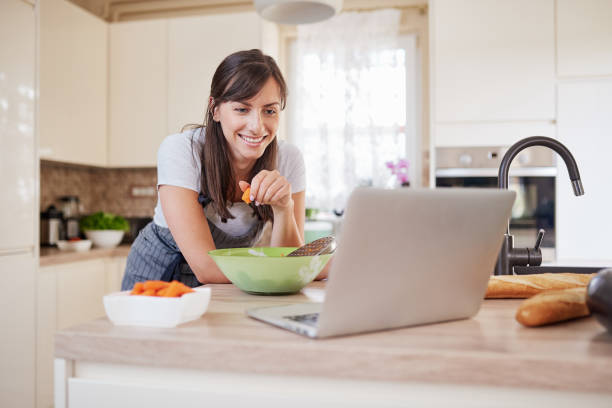 istock Woman looking at recipe on laptop while standing in kitchen. 1162147196