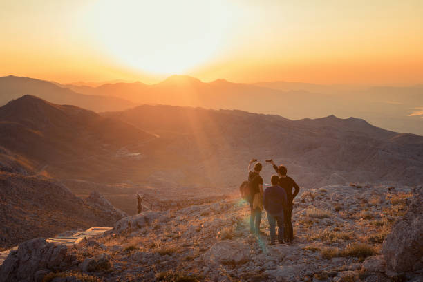 istock Four happy tourists greetings sunrise in mountains 1162147970