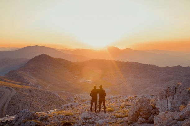 istock Two happy tourists greetings sunrise in mountains 1162148030