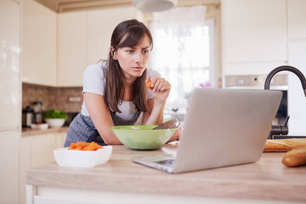 istock Woman looking at recipe on laptop while standing in kitchen. 1162148182
