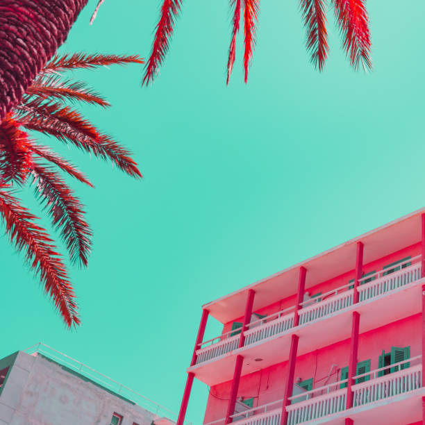 strandhotel und teil der palmblätter im infrarot-stil. tropisches reisekonzept. minimalismus und surreal. weiche lichtfarben - pink buildings stock-fotos und bilder