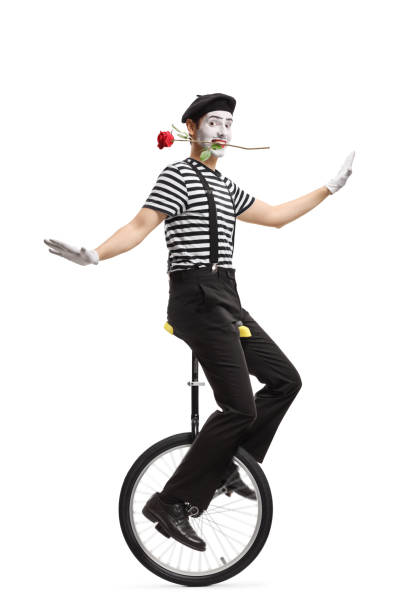istock Mime riding a unicycle with a red rose in his mouth 1162153819