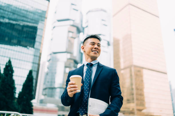 istock Businessman holding coffee cup and documents on street 1162156249