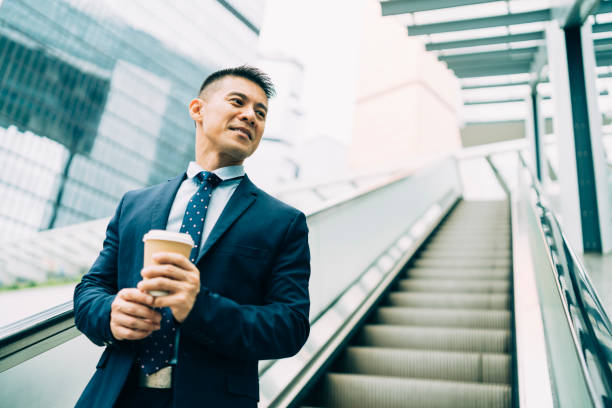 Smiling businessman moving down on escalator at workplace