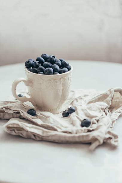 istock Blueberry in a old rustic style mug on white background 1162156386