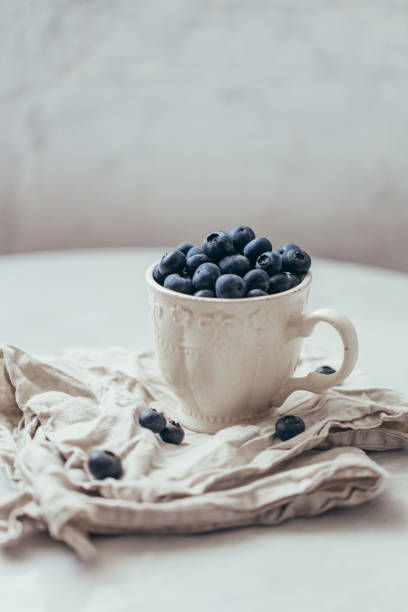 istock Blueberry in a old rustic style mug on white background 1162156391