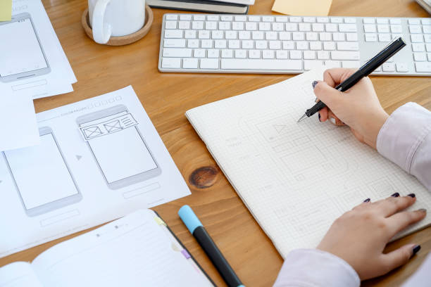 istock Female designer  drawing and designing UI UX application or website on paperwork at office. 1162159406