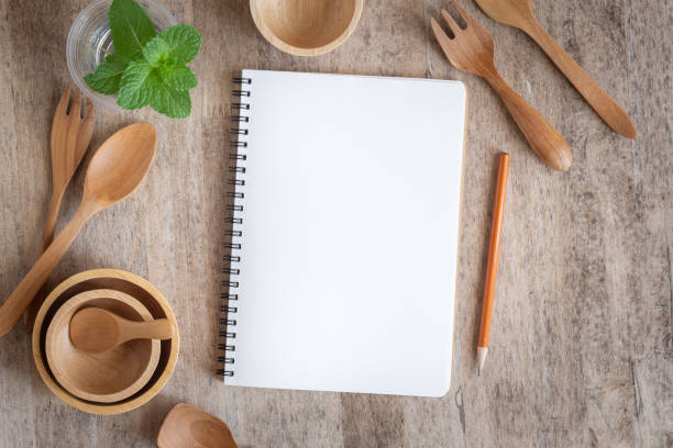 istock Blank notebook for text note on wooden table background. On wooden have spoon fork and pencil 1162160326
