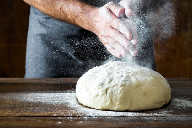 istock Man preparing bread dough on wooden table in bakery 1162163968