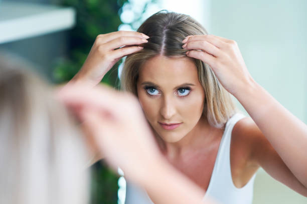 Happy woman brushing hair in bathroom having problem with hair loss stock photo