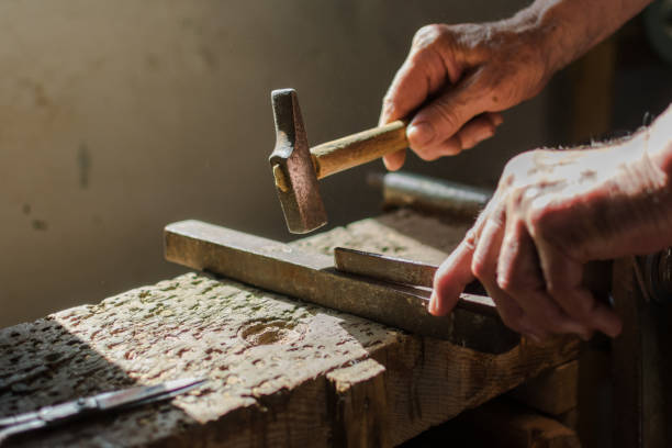 istock Hands of an elderly man working on the iron with the hammer. 1162166204