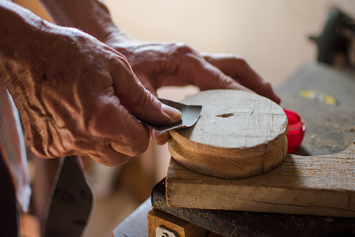 Elderly hands scrubbing wood by sandpaper. Lifestyle concept, worker.