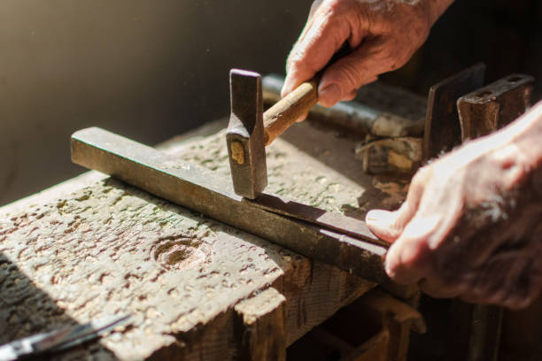 istock Hands of an elderly man working on the iron with the hammer. 1162166222
