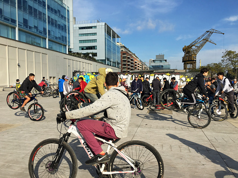 Buenos Aires, Argentina - July 14, 2019: Group of young boys hanging out together riding bikes and showing off their skills in Puerto Madero neighborhood. This gatherings are already customary and they hold them every sunday