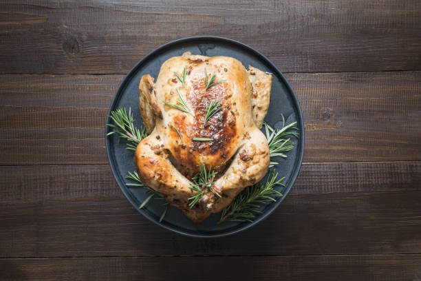 istock Traditional roasted chicken with rosemary on wooden table. Top view. 1162168043