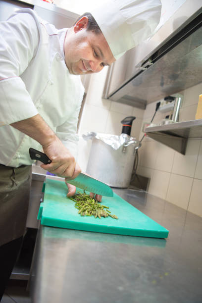 istock Smiling Chef in the Restaurant Kitchen Chopping Asparagus 1162168572