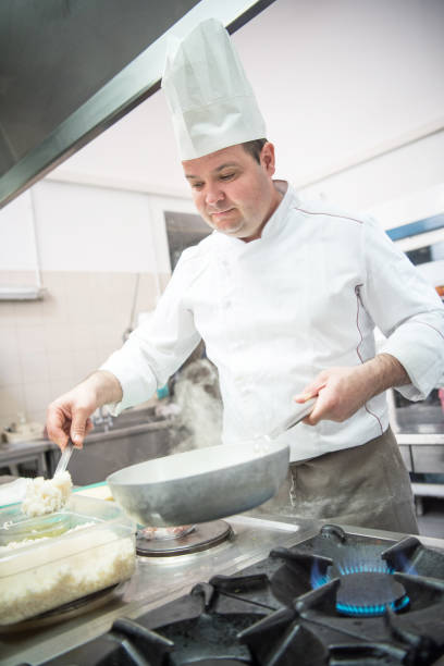 istock Professional Chef in the Restaurant Kitchen Preparing Dish of Risotto with Asparagus 1162168577