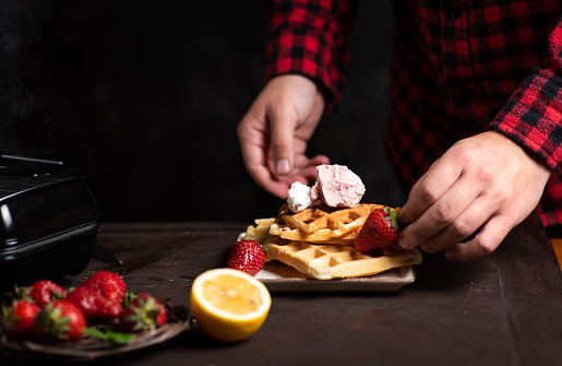 istock Chef adding strawberries on a waffle close up 1162177174