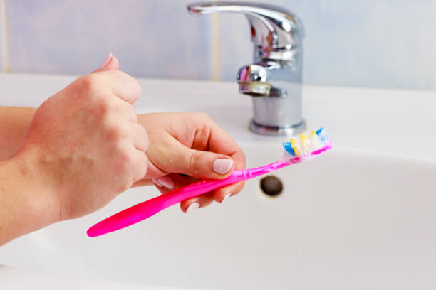 istock Hand holding toothbrush in bathroom 1162186998