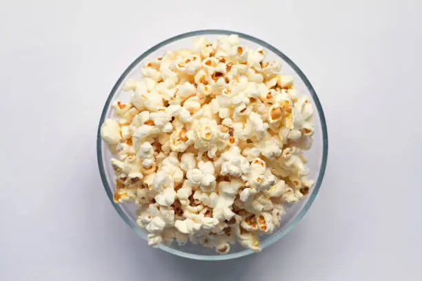 Photo of bowl of popcorn isolated on white background top view