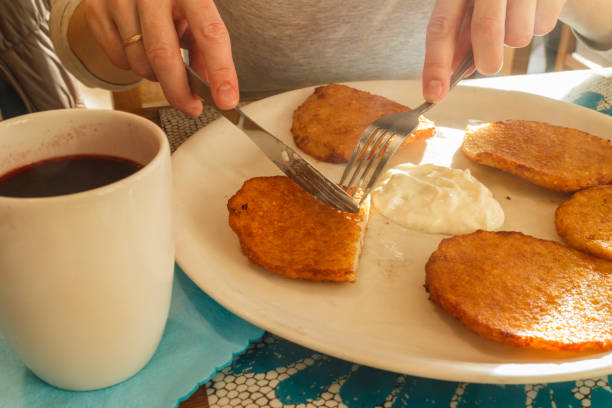 Delicious potato pancakes on plate with sour cream