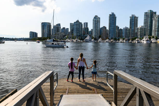 Family on vacation in Vancouver, Canada Mother and daughters travelling in Vancouver, British Columbia. Family with Vancouver skyline. false creek stock pictures, royalty-free photos & images