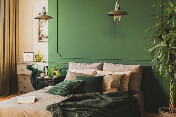 istock Two industrial lamps above comfortable double bed with cozy bedding, copy space on empty wall 1162195523